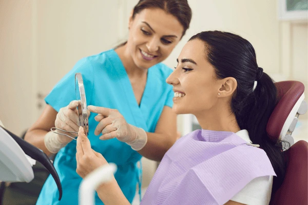 A person looking at a mirror and whitening their teeth with a gentle Corby
